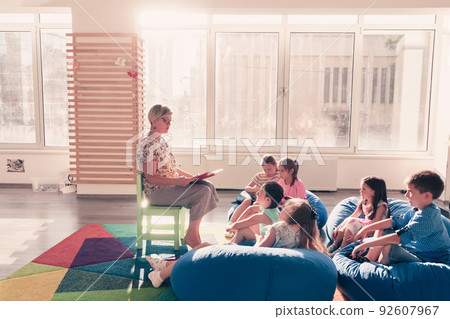 Reading time in elementary school or kindergarten, teacher reading a book to kids in elementary school or kindergaden. Selective focus Reading time in elementary school or kindergarten, teacher reading a book to kids in elementary school or kindergaden. Selective focus 92607967