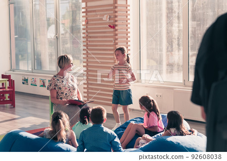 Reading time in elementary school or kindergarten, teacher reading a book to kids in elementary school or kindergaden. Selective focus  92608038