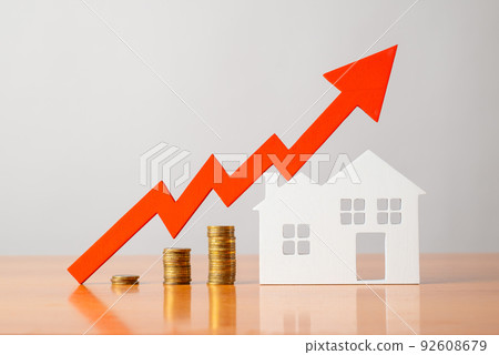 Coins on a table, a red up arrow and house. The concept of the rising price of real estate Coins on a table, a red up arrow and house. The concept of the rising price of real estate 92608679