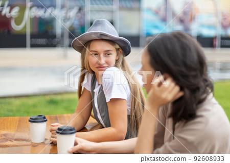 Pretty young woman listening to her friend drinking coffee 92608933