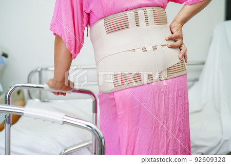 Asian senior pain back wearing elastic support belt with walker. 92609328