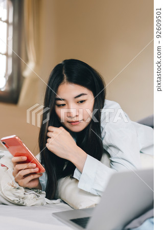 Young adult single woman using smartphone in the moring for social message app chat with friend 92609501
