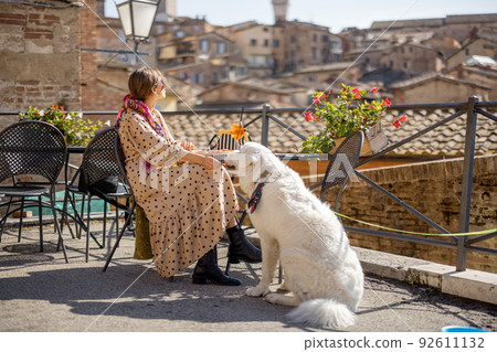 Woman feeds her dog while sitting at restaurant in SIena, Italy 92611132