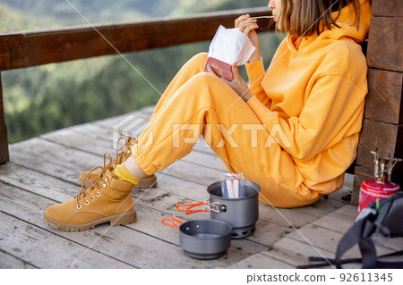 Woman eats while traveling in the mountains Woman eats while traveling in the mountains 92611345