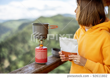 Woman prepares freeze-dried food for hiking in mountains Woman prepares freeze-dried food for hiking in mountains 92611802