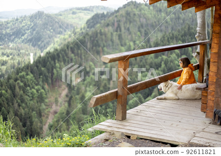 Woman sits relaxed with her dog in the mountains 92611821