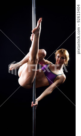 The strong and graceful young girl performing acrobatic exercises on pylon 92613404