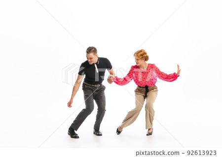 Portrait of stylish young couple, man and woman dancing isolated over white studio background. 60s, 70s lifestyle Portrait of stylish young couple, man and woman dancing isolated over white studio background. 60s, 70s lifestyle 92613923