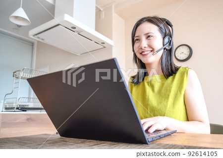 Image cut headset of a young woman working from home 92614105