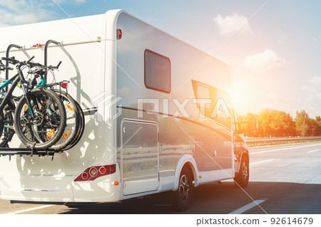 Scenic view big modern white family rv camper van vehicle driving on european highway road against blue sky in summer day. Rving motorhome lifestyle travel and adventure tourism trip journey concept 92614679