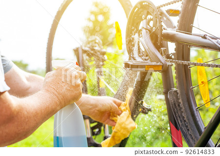 Senior man hand cleaning the bike by spray and a rag, doing maintenance of his bicycle, sport concept Senior man hand cleaning the bike by spray and a rag, doing maintenance of his bicycle, sport concept 92614833