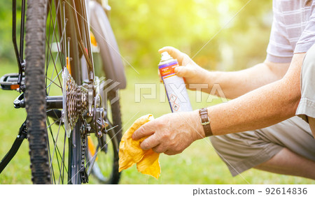 Senior man doing maintenance for his bicycle during summer time, oiling his chain of the bike, healthy lifestyle Senior man doing maintenance for his bicycle during summer time, oiling his chain of the bike, healthy lifestyle 92614836