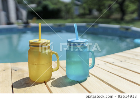 two cocktails of yellow and blue standing by the pool. Pool party outdoors 92614918
