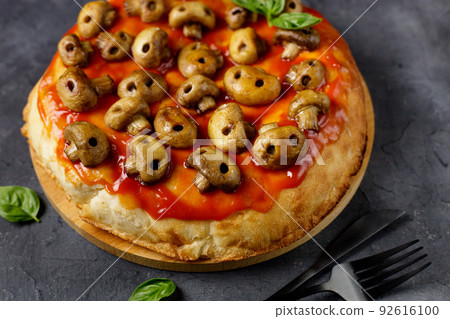 Homemade pizza with tomato sauce and mushrooms in the form of skulls. Concept for Halloween celebrations Homemade pizza with tomato sauce and mushrooms in the form of skulls. Concept for Halloween celebrations 92616100