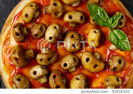 Homemade pizza with tomato sauce and mushrooms in the form of skulls. Concept for Halloween celebrations Homemade pizza with tomato sauce and mushrooms in the form of skulls. Concept for Halloween celebrations 92616101
