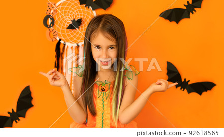 The female pointing fingers in different sides at copy space on an orange studio background with halloween decorations. Pretty cute girl with colored hair. The female pointing fingers in different sides at copy space on an orange studio background with halloween decorations. Pretty cute girl with colored hair. 92618565