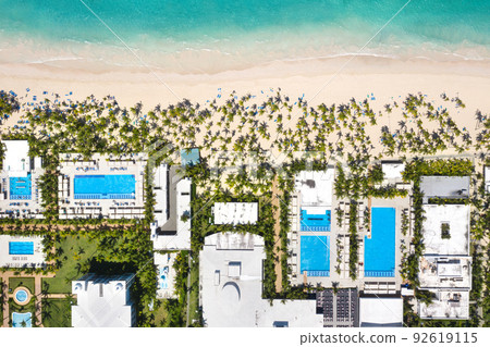 Outdoor poolside with swimming pools, coconut palm trees near sandy tropical beach. Caribbean travel. Aerial top view 92619115