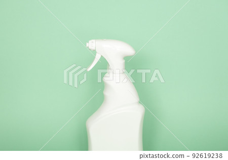 White plastic spray bottle for liquid cleaning products isolated on green background. Packaging mockup bottle with sprayer. 92619238