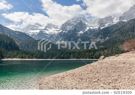 Gently sloping shore of a high-mountain alpine lake Tovel, descending to emerald water 92619300