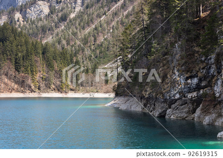 Steep rocky shore of the alpine lake Tovel, covered with centuries-old pines and firs Steep rocky shore of the alpine lake Tovel, covered with centuries-old pines and firs 92619315