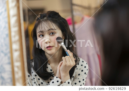 一個年輕的女人，在鏡子裡化妝 92619829
