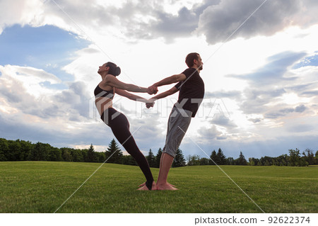 Young healthy couple doing acro yoga in the sunny summer park. Fitness and healthy lifestyle 92622374