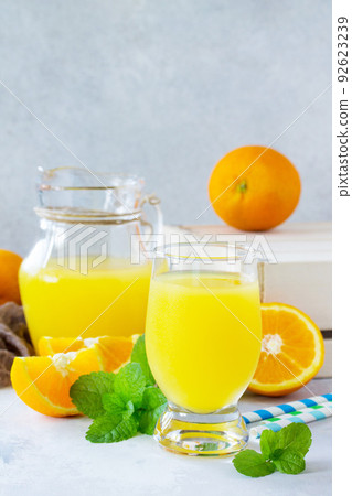 A refreshing summer drink with orange juice, fresh oranges and mint on a gray stone or slate background. A refreshing summer drink with orange juice, fresh oranges and mint on a gray stone or slate background. 92623239