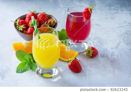 Refreshing summer drinks assortment. Orange juice, strawberry juice, fresh oranges and strawberries on a gray stone or slate background. Copy space. 92623245