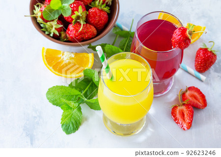 Refreshing summer drinks assortment. Orange juice, strawberry juice, fresh oranges and strawberries on a gray stone or slate background. 92623246