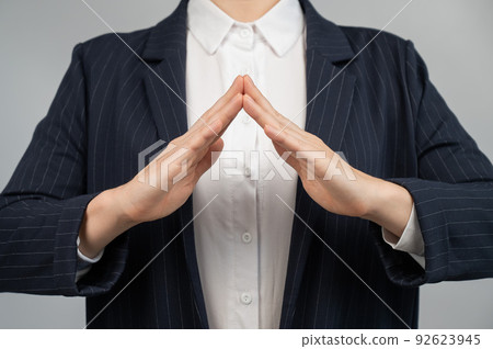 Business woman in a suit holding her hands in the shape of a house. Business woman in a suit holding her hands in the shape of a house. 92623945