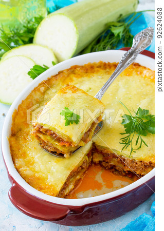 Homemade lasagna with Bolognese sauce of zucchini and minced meat on blue concrete or stone background. Homemade lasagna with Bolognese sauce of zucchini and minced meat on blue concrete or stone background. 92624088