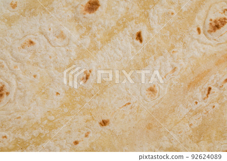 Plain wheat tortilla wraps. Spanish or Mexican circular unleavened flatbread from wheat flour. Ingredient for cooking fast food or snack. Closeup, texture background Plain wheat tortilla wraps. Spanish or Mexican circular unleavened flatbread from wheat flour. Ingredient for cooking fast food or snack. Closeup, texture background 92624089