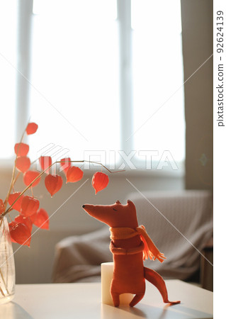 autumn still life with a toy fox, flowers, twigs of red physalis in a vase in a cozy home interior autumn still life with a toy fox, flowers, twigs of red physalis in a vase in a cozy home interior 92624139