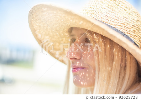 Beautiful blond woman in a straw hat. 92625728