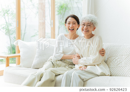 Smiling parent and child relaxing in the living room (middle, senior, female, mother and child, daughter-in-law, mother-in-law) 92626423