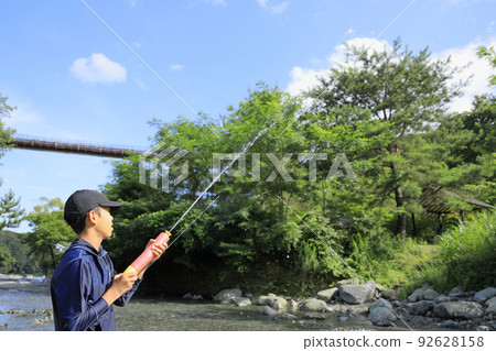Male junior high school student (12 years old) playing in the river with a water gun 92628158