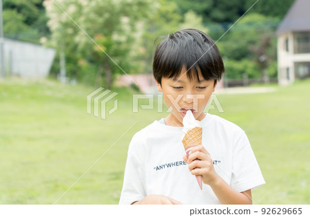 Asian kid eating soft serve ice cream in a fresh green park Asian kid eating soft serve ice cream in a fresh green park 92629665