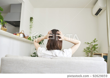 Back view of a woman holding her head in the living room 92629859