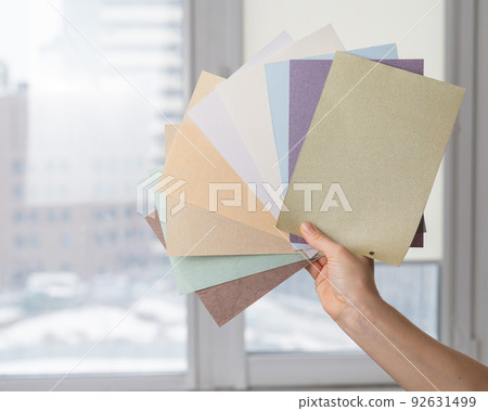 Woman holding fabric samples of roller blinds against window background. Woman holding fabric samples of roller blinds against window background. 92631499