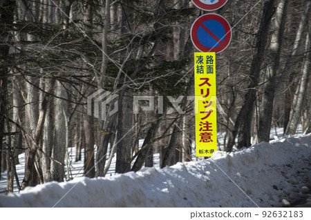 A slip warning sign placed on a road in winter 92632183
