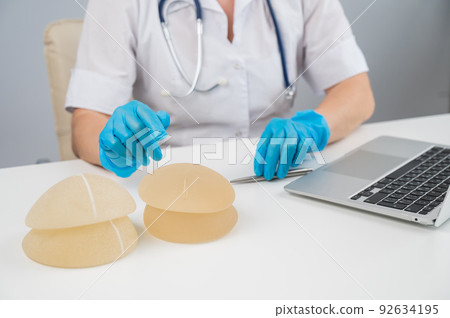 Doctor plastic surgeon explains the benefits of different breast implants.  92634195