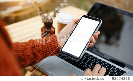 professional businesswoman holding a blank screen smartphone in modern office room professional businesswoman holding a blank screen smartphone in modern office room 92634228