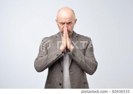 Miserable mature man in casual suit with begging expression, asks for favor, keeps hands in praying gesture. Miserable mature man in casual suit with begging expression, asks for favor, keeps hands in praying gesture. 92636535