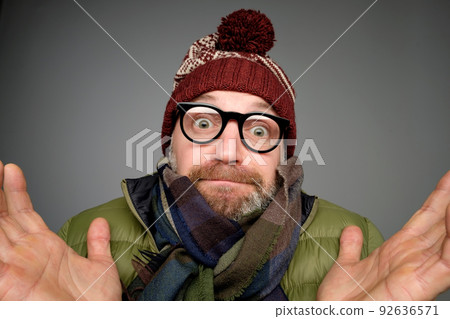 Portrait of confused mature man in warm winter clothes standing over gray background gesturing with hands. Portrait of confused mature man in warm winter clothes standing over gray background gesturing with hands. 92636571