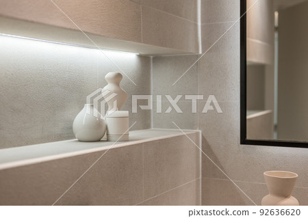 A corner of stylish bathroom with accessories. Detail shot of a shelf with candle and ceramic vases. Home decoration and elumination concept 92636620