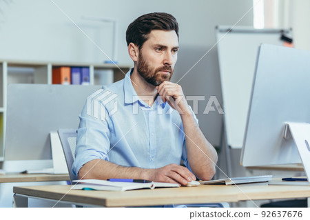 The focused designer works in a modern studio office, the man works during the day at the computer The focused designer works in a modern studio office, the man works during the day at the computer 92637676