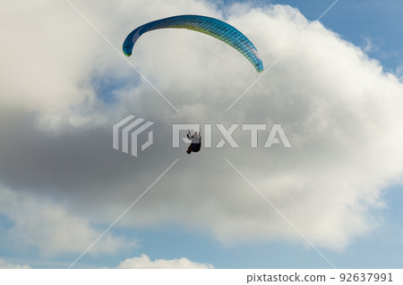 Paraglider flying over clouds in summer day 92637991