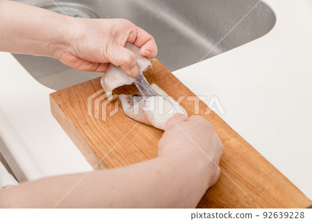 [A middle-aged housewife prepares a squid, removing the enpera] 92639228