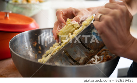 Closeup view of a woman grating an apple using a steel grater 92639453