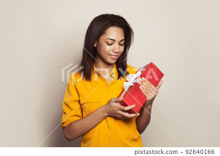 Beautiful black woman looking at red gift on white background Beautiful black woman looking at red gift on white background 92640166